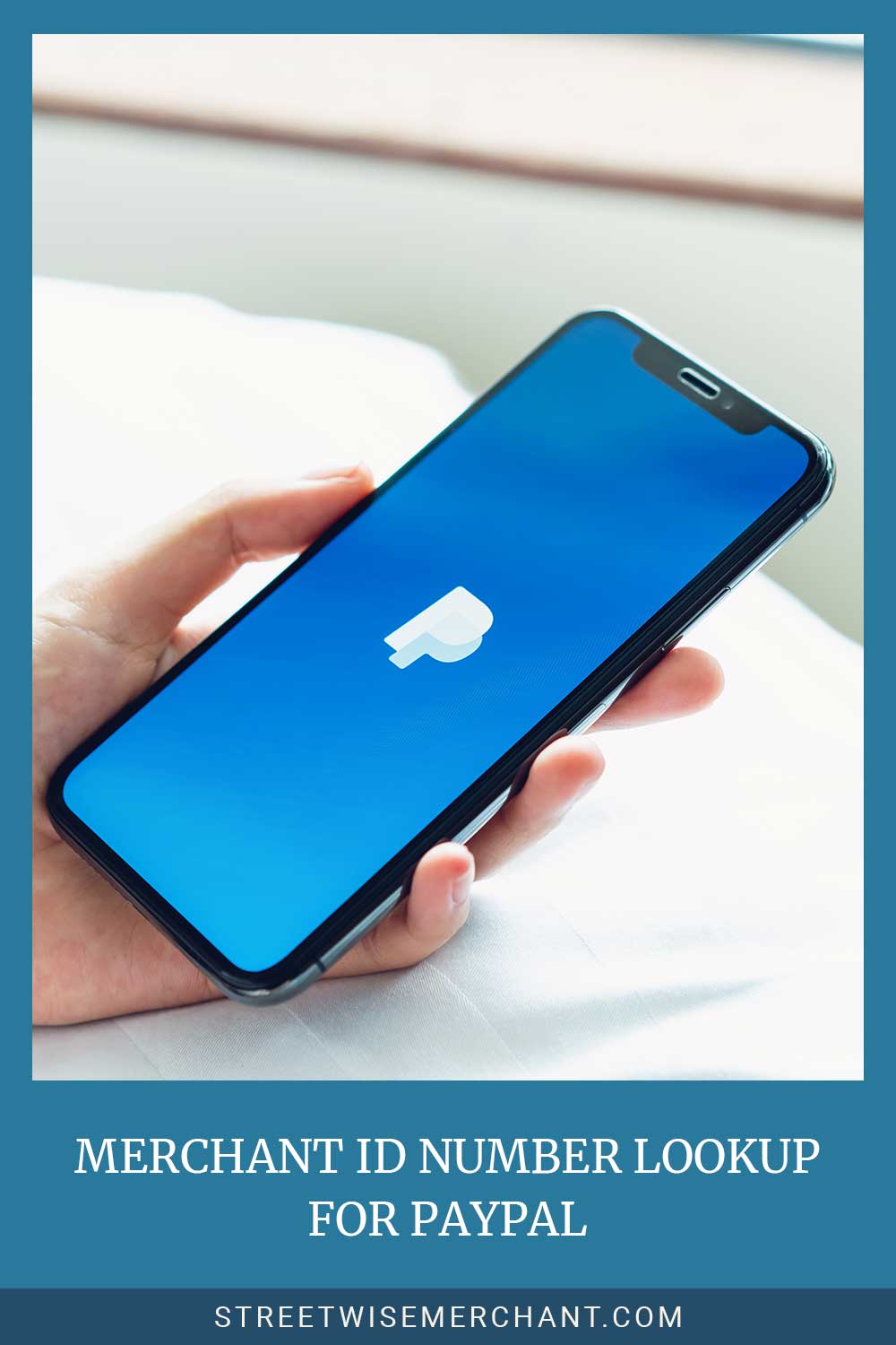 Hand holding a phone with PayPal logo on the screen - Merchant ID Number Lookup For PayPal